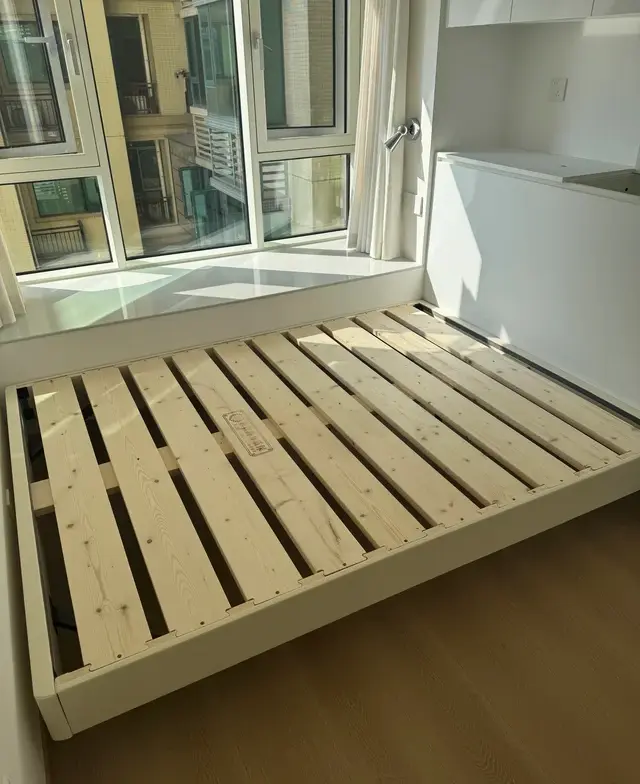 Pine bed frame with visible wood slat support in a sunlit bedroom