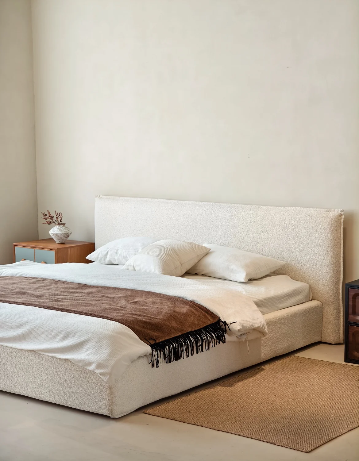 Light upholstered bed with a tall headboard, white bedding and bedside storage cabinets
