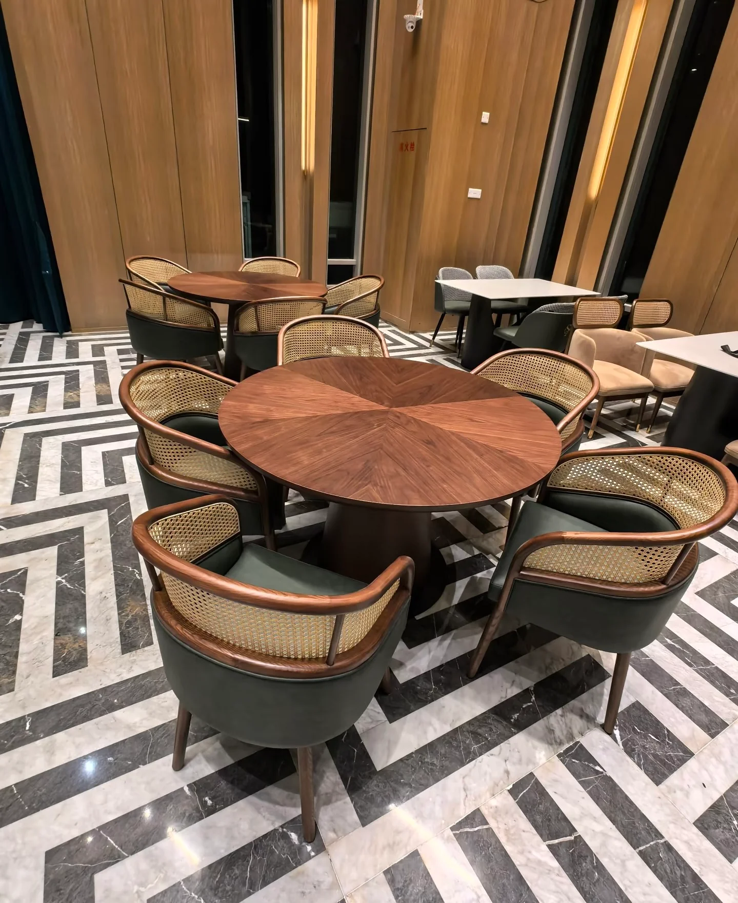 Round timber dining table surrounded by cane-backed upholstered chairs