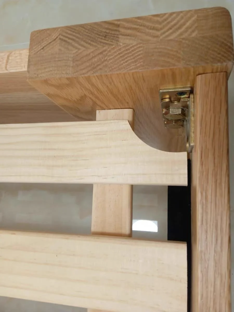 Close-up of a bed-frame corner, timber grain and a metal connection fitting