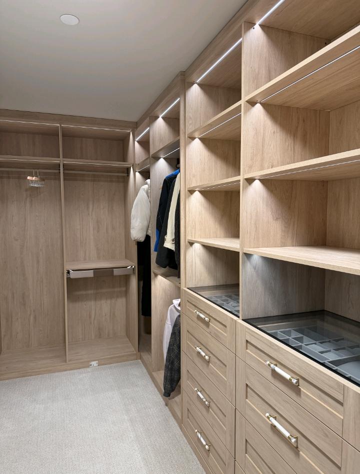 Closet seen from the opposite end with glass-topped drawers and a leaning floor mirror