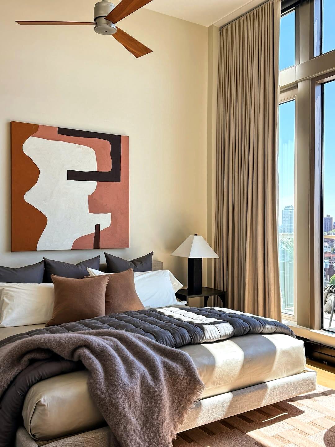 Warm bedroom with city view and abstract art