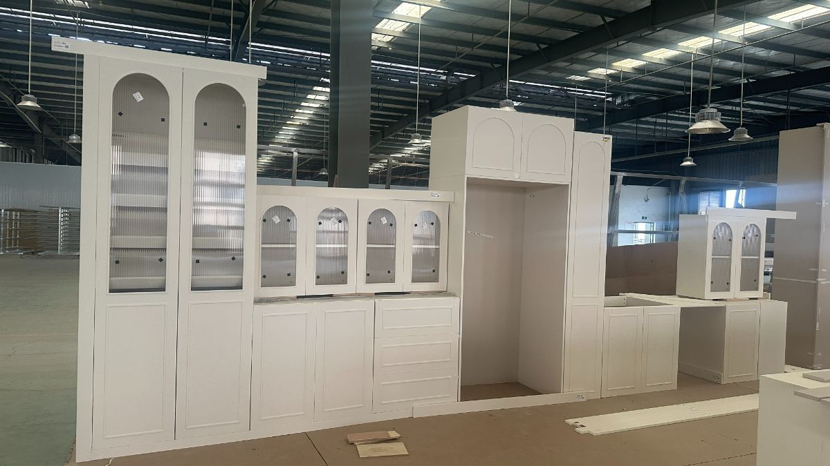 Arched fluted-glass wall cabinets lined up on the factory floor